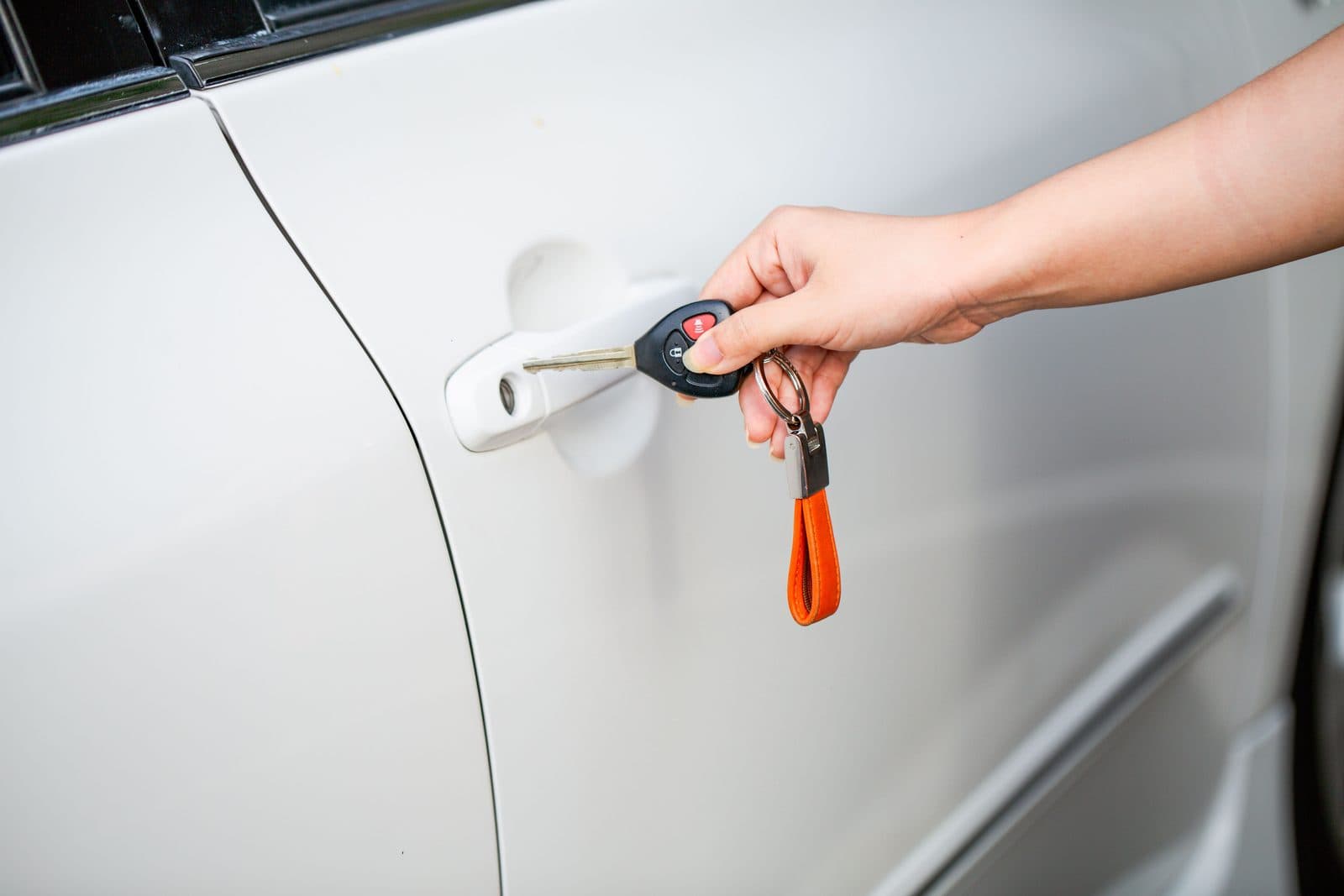 Hand holding a car key next to a locked car door
