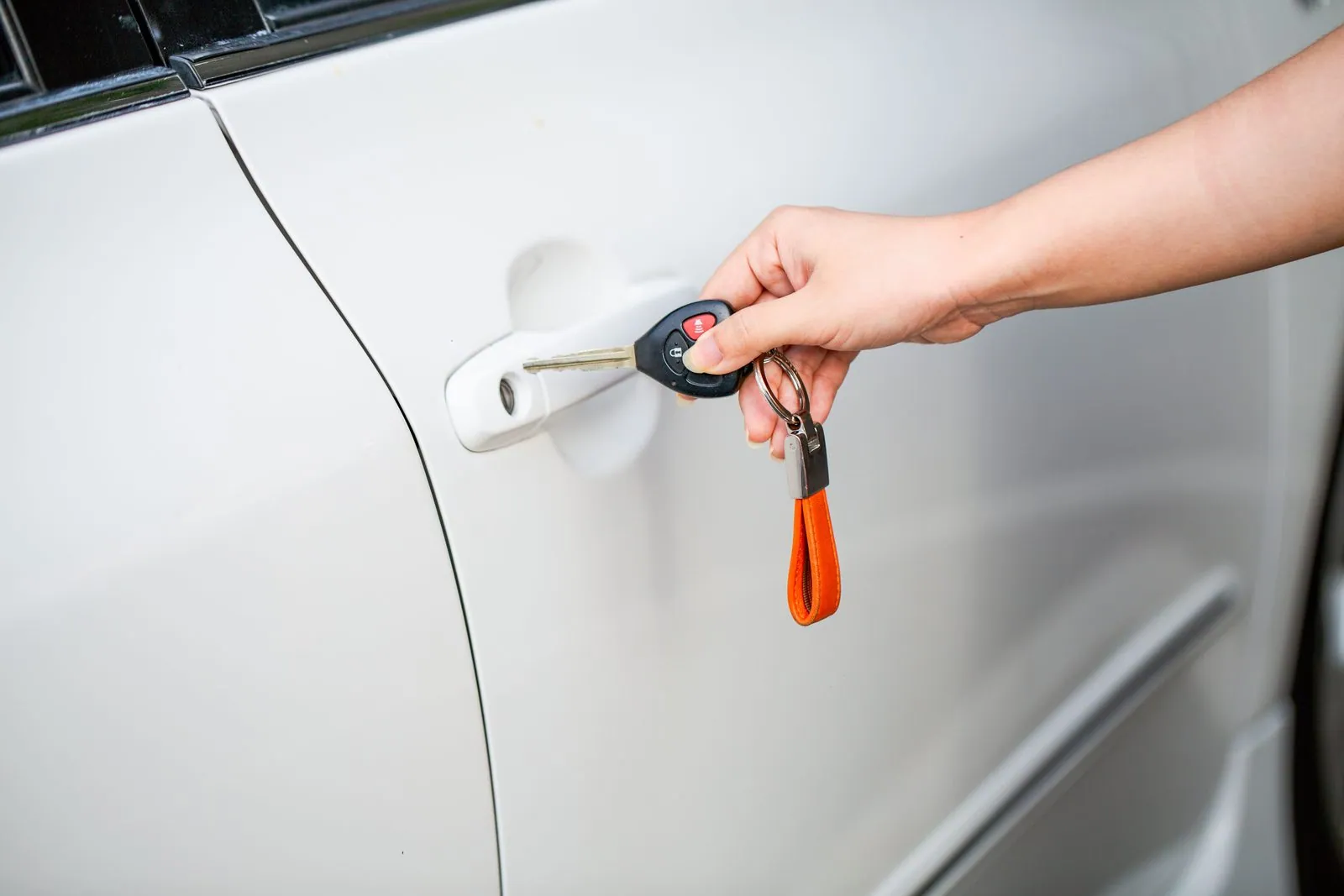 Hand holding a car key next to a locked car door